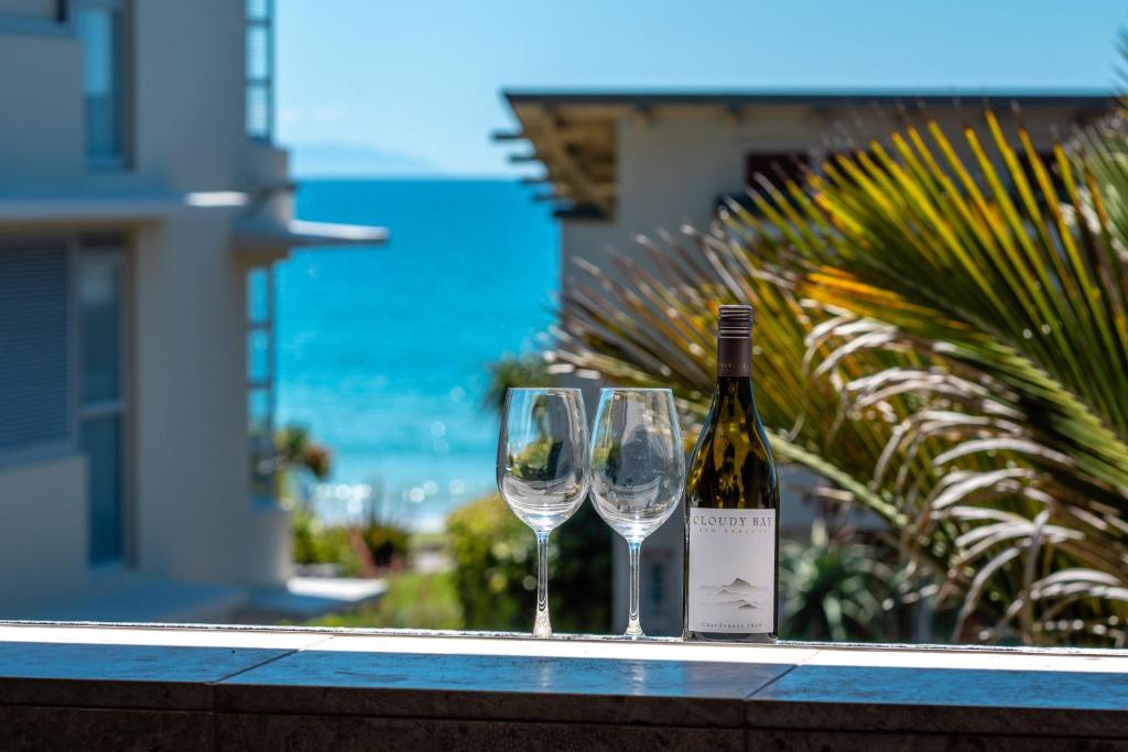 a bottle of wine and two wine glasses on a ledge at The Sands - Apartment 12 in Onetangi