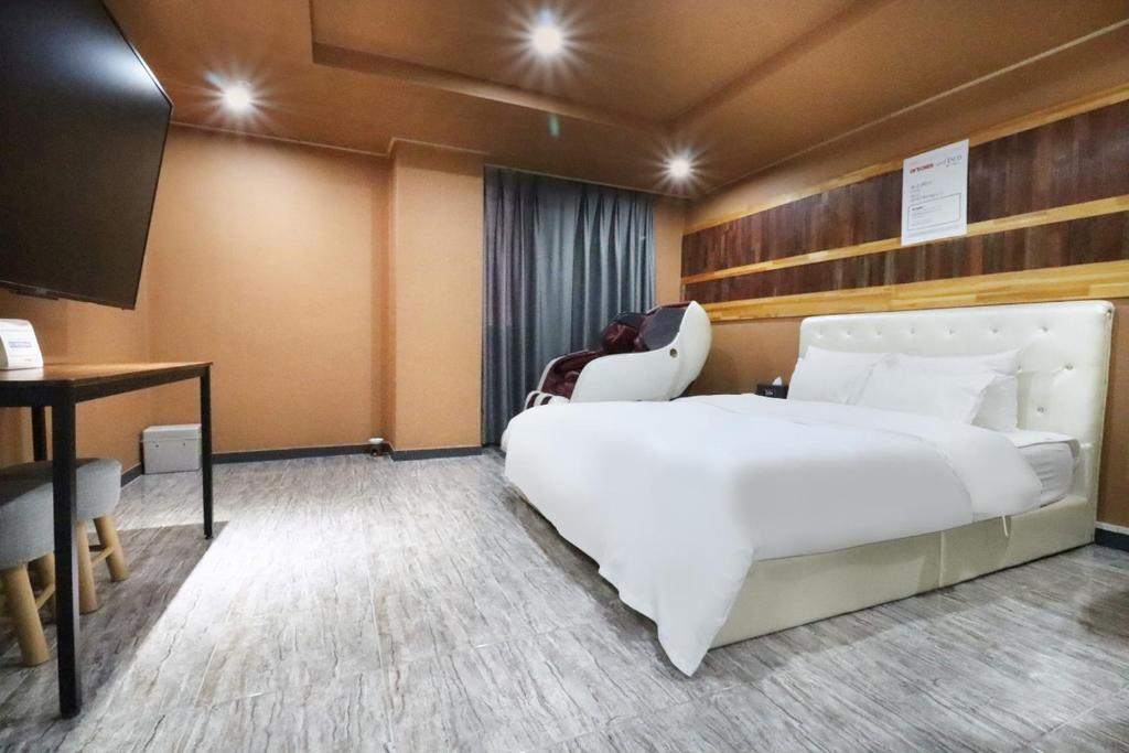 Habitación de hotel con cama blanca grande y escritorio. en Hotel Don en Changwon