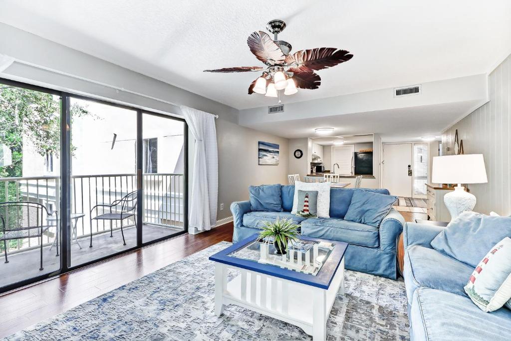 uma sala de estar com um sofá azul e uma mesa em 2023 Beach Wood em Fernandina Beach