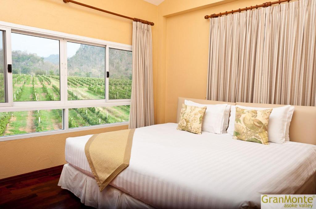 a bedroom with a bed with a large window at GRANMONTE Wine Cottage in Phayayen