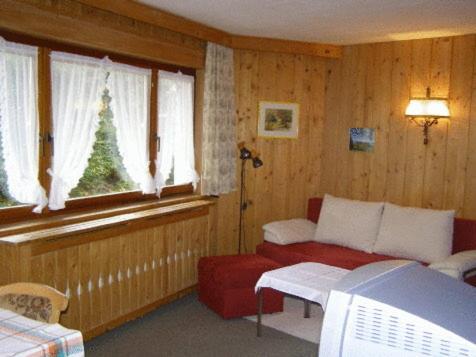 a living room with a red couch and windows at Landhaus Brigitta in Innsbruck