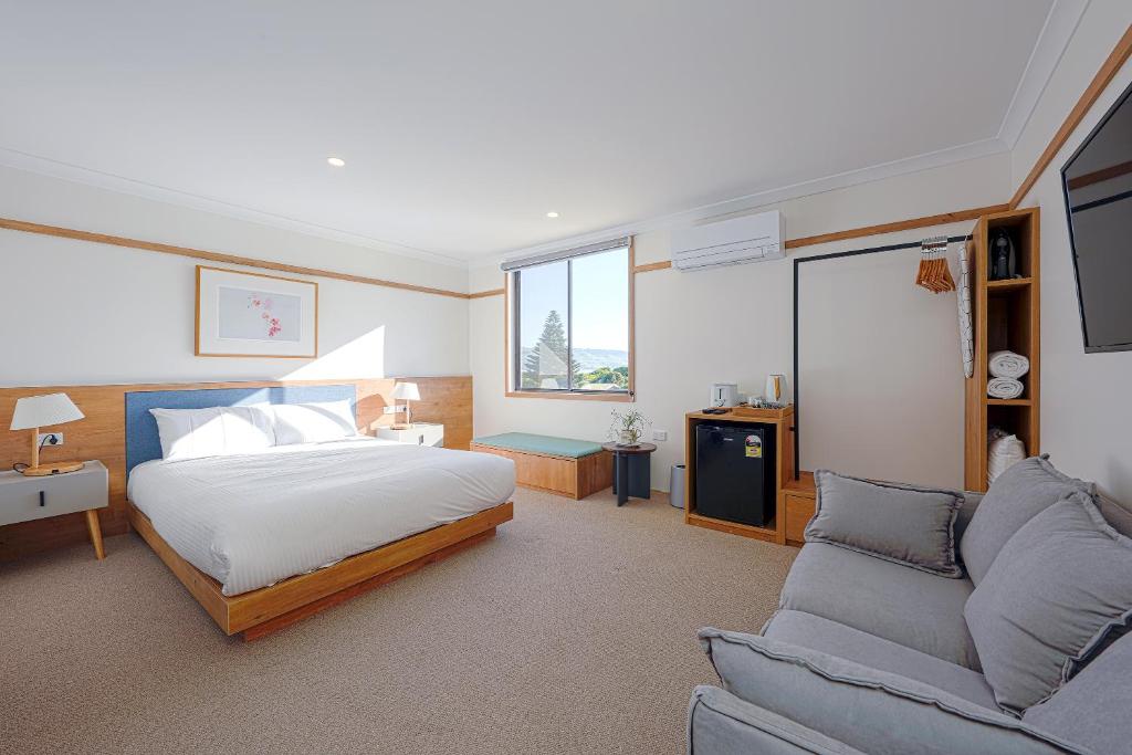 een slaapkamer met een bed en een bank bij Blue Ocean Motel Apollo Bay in Apollo Bay