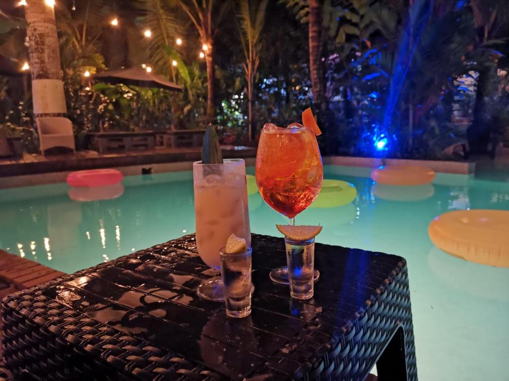 three cocktails on a table next to a swimming pool at Monkey Lodge Panama in Chilibre