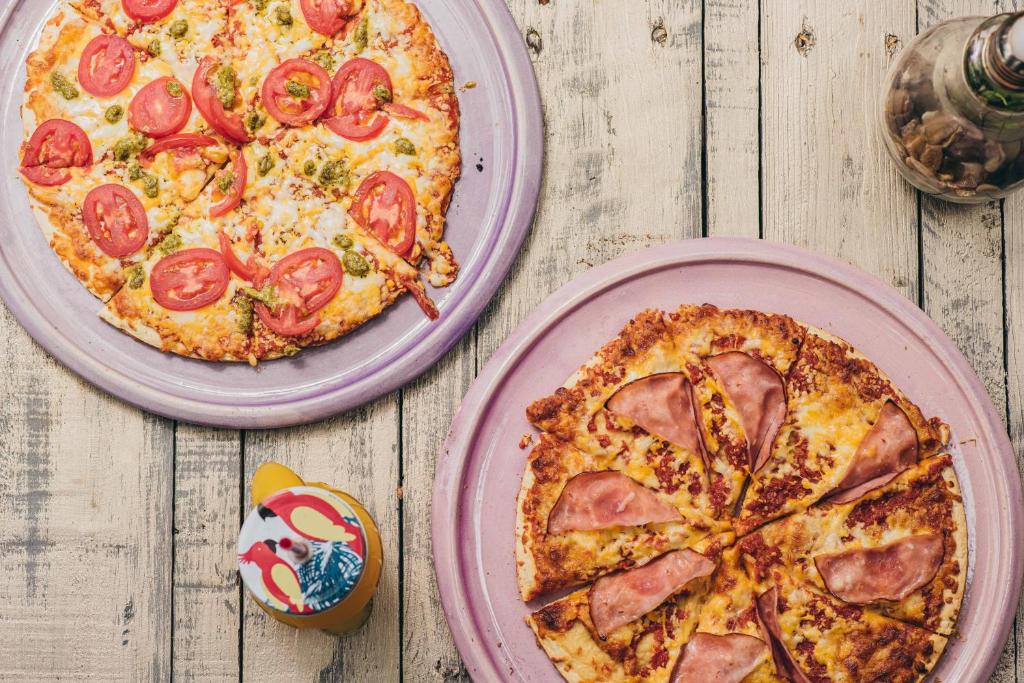 two pizzas on pink plates on a wooden table at Monkey Lodge Panama in Chilibre