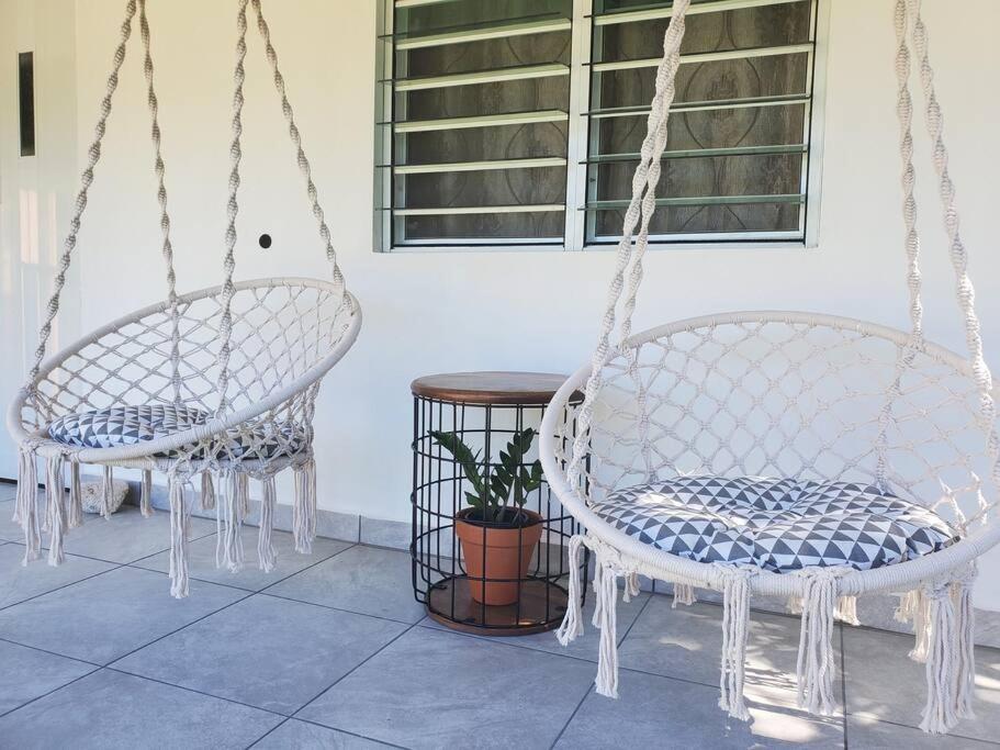 two swinging chairs and a table in a room at Aguadilla Sunset Apt AC WiFi 8 minute walk Crashboat Beach in Aguadilla
