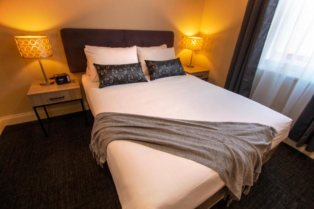 a bedroom with a large white bed with two lamps at Whyalla Playford Apartments in Whyalla