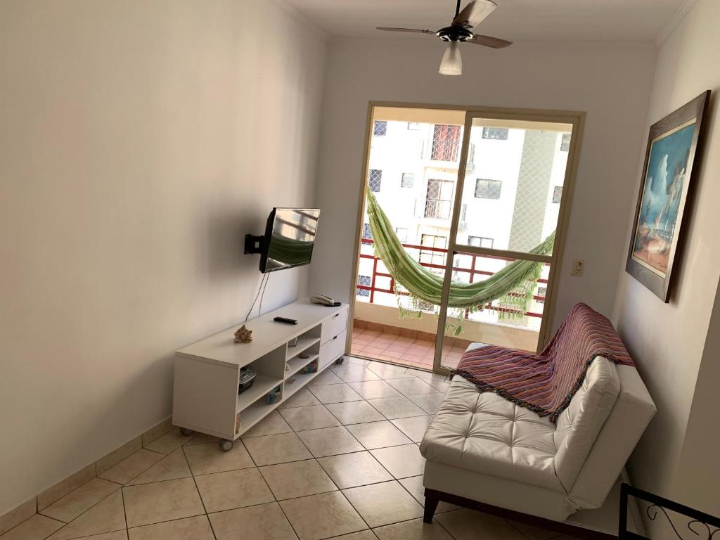 sala de estar con sofá, silla y ventana en Apartamento Enseada, en Guarujá