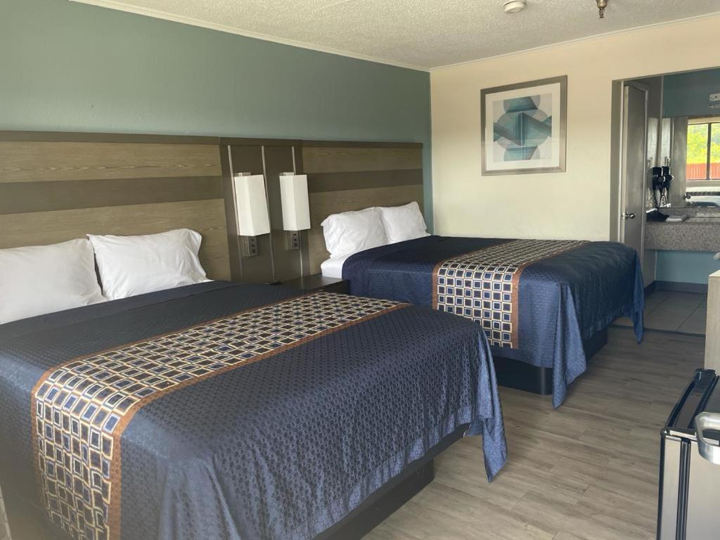 una camera d'albergo con due letti con lenzuola blu di Executive Inn & Suites a Beaumont