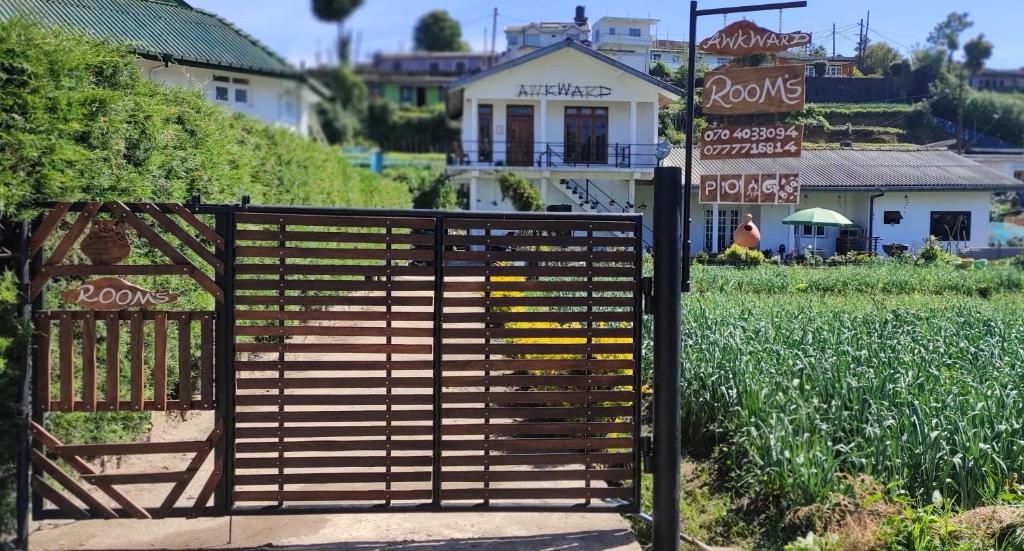ein Tor vor einem Feld mit einem Haus in der Unterkunft RC AWKWARD in Nuwara Eliya