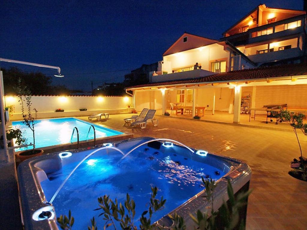 a swimming pool in front of a house at night at Apartments Denko - with pool in Kali