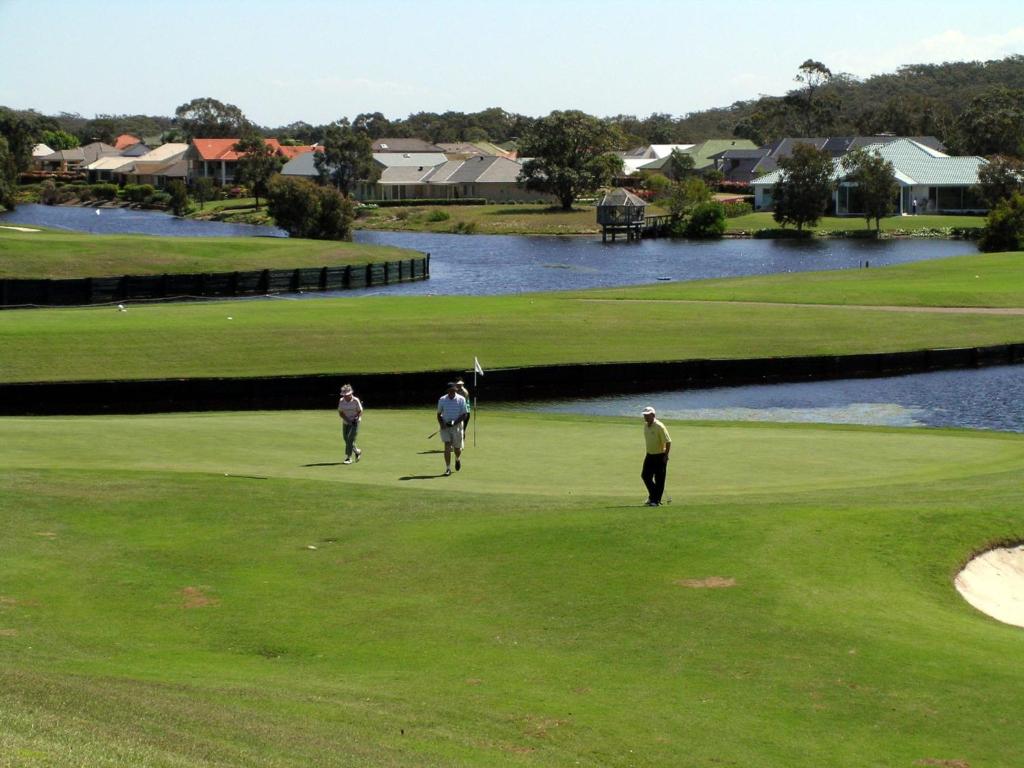 un grupo de tres personas jugando en un campo de golf en Horizons Retreat, en Salamander Bay