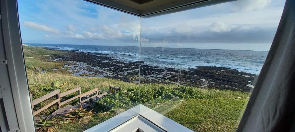 una ventana de la casa con vistas al océano en Whitewaters, 2 Bedroom Apartment en Sea View