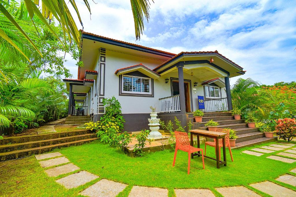 a house with a table and chairs in front of it at FabEscape Vagator Retreat Resort With Swimming Pool in Goa Velha