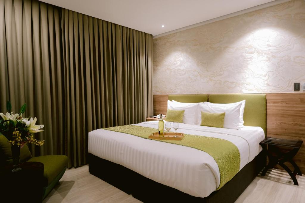 um quarto de hotel com uma cama grande e uma mesa em Goldberry Suites and Hotel Cebu em Cebu