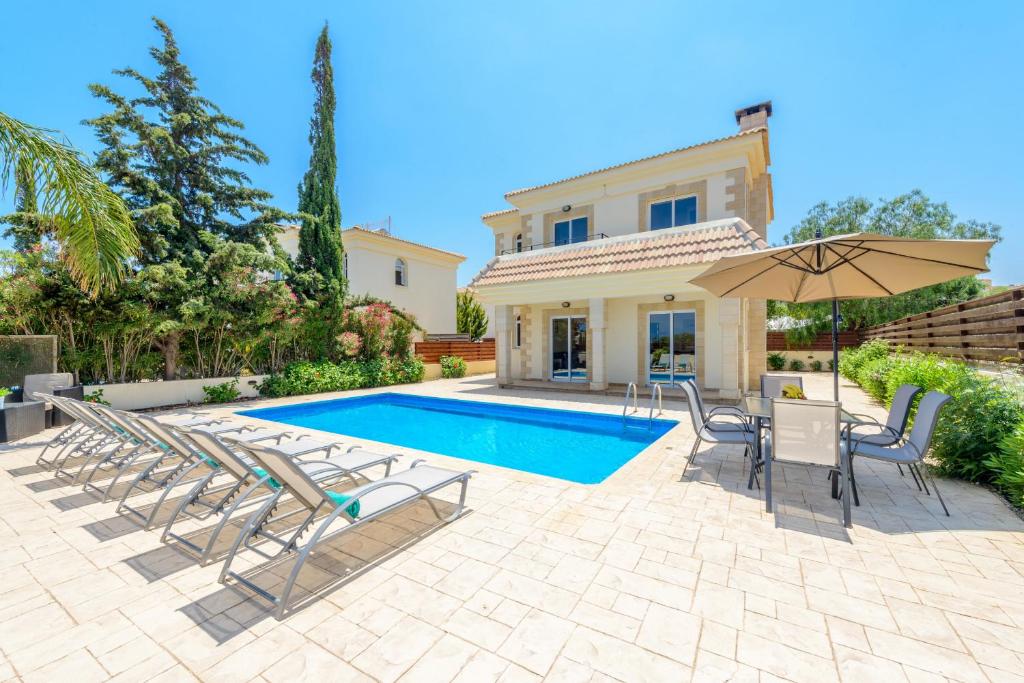 eine Villa mit einem Pool mit Stühlen und einem Sonnenschirm in der Unterkunft Villa Irina in Paralimni