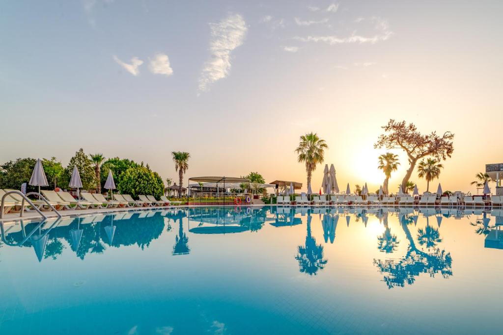 a pool at a resort with chairs and palm trees at Armas Gul Beach in Kemer