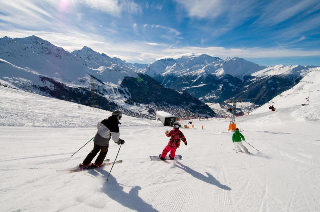 a group of people skiing down a snow covered mountain at Hotel Montpelier in Verbier
