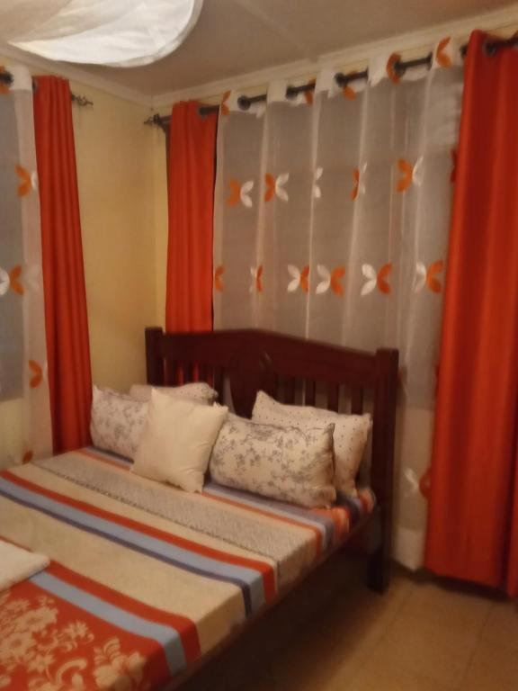 a bedroom with a bed with orange curtains at Tamara One Bedroom Apartment in Shanzu in Mombasa