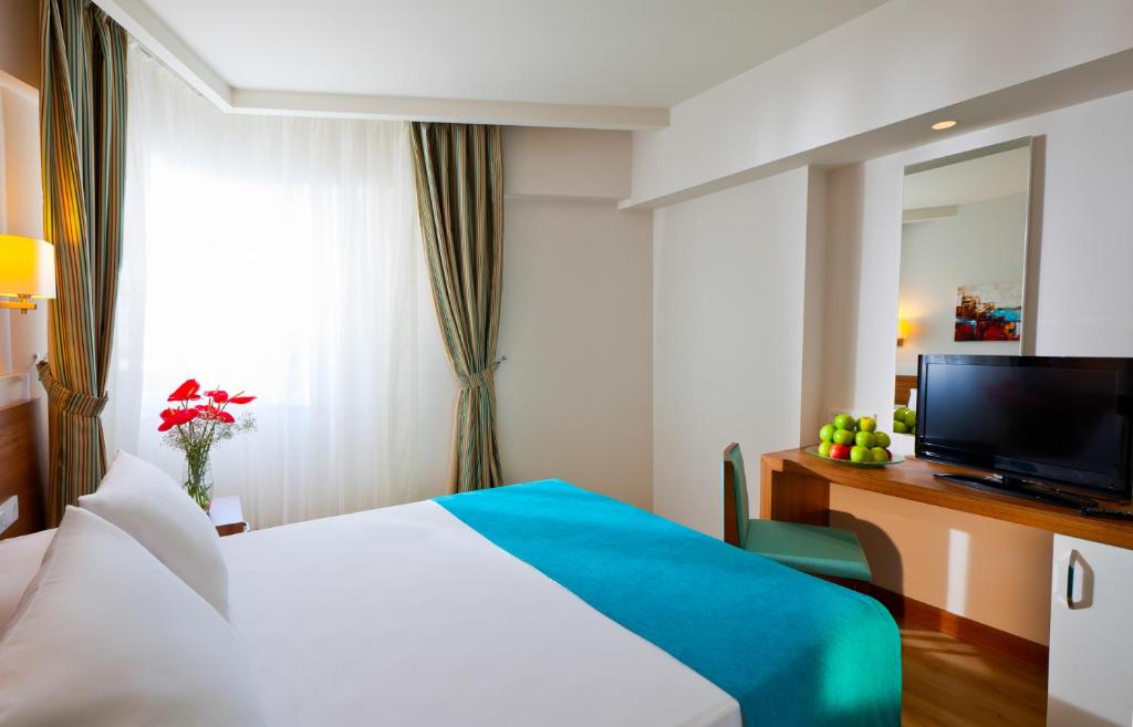 a hotel room with a bed and a television at Grand Park Lara Hotel in Lara