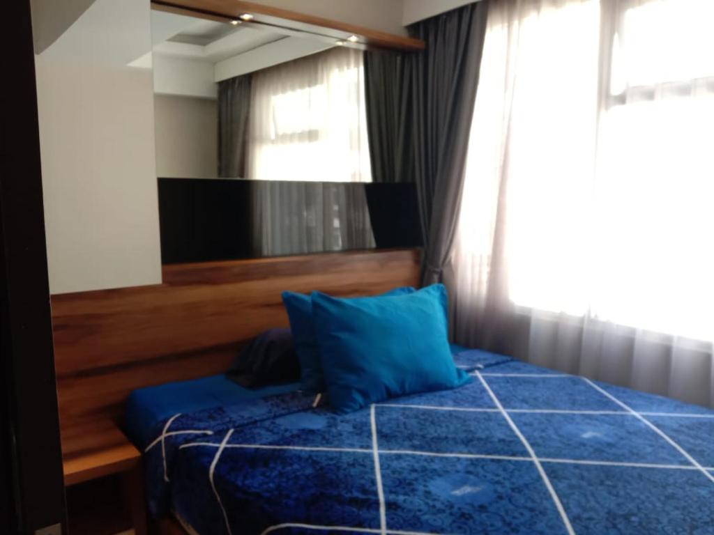 a bedroom with a blue bed and a mirror at Raja Apartemen Jarrdin Type 33 in Bandung