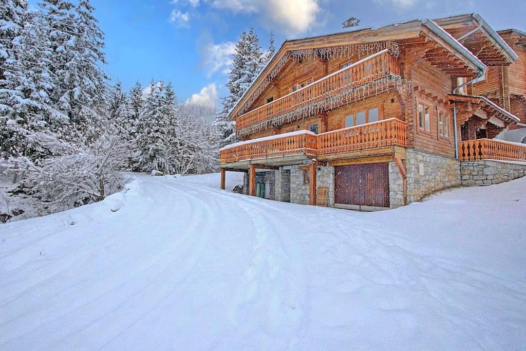 a wooden house in the snow with a snow covered driveway at Chalet Jonquilles - Au pied des pistes de La Tania in Courchevel