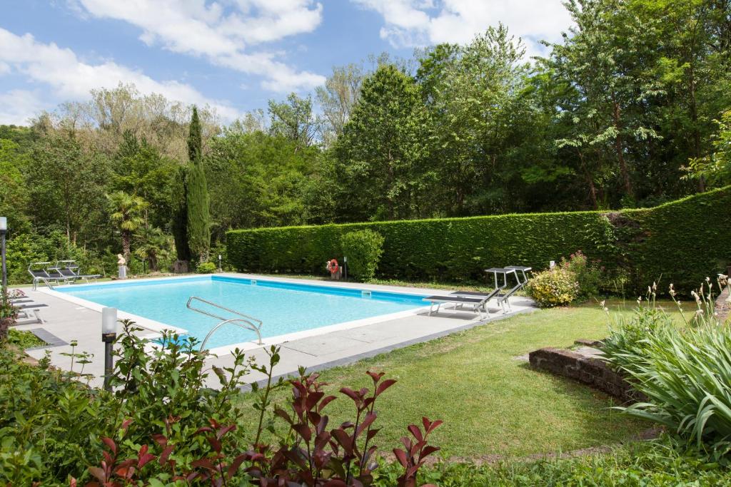 a swimming pool in a garden with bushes at Art Hotel Pandos in Tabiano