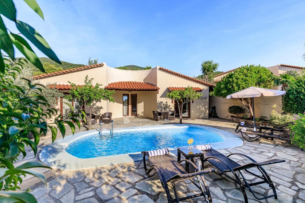 a swimming pool with chairs and a house at Skopelos Holidays Hotel & Spa in Skopelos Town