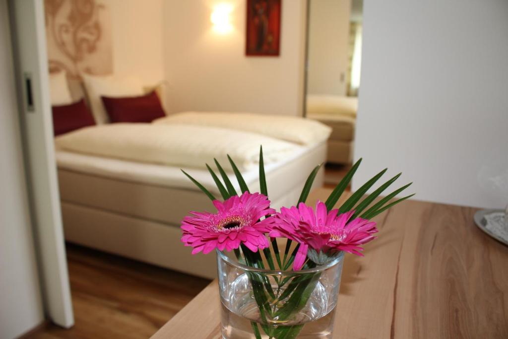 un vase avec des fleurs roses assises sur une table dans l'établissement Hotel Rebstöckle, à Hagnau am Bodensee