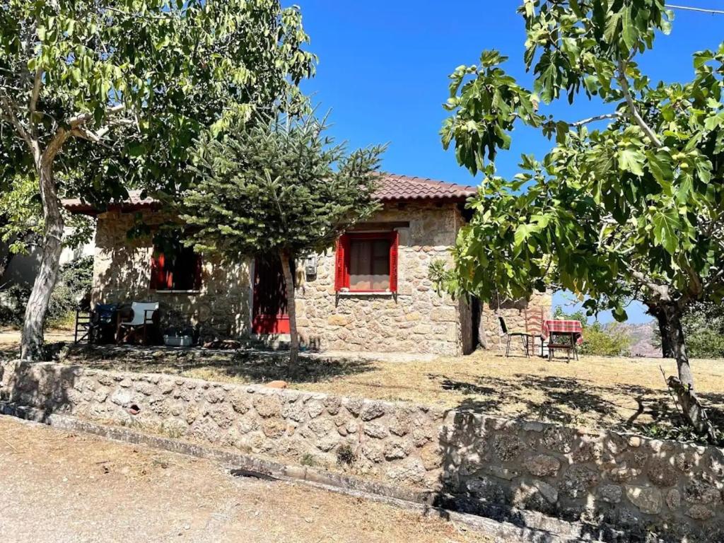 Casa de piedra con ventana roja y pared de piedra en ΦΙΛΥΡΑ ΠΕΤΡΙΝΟ, en Kernitsa