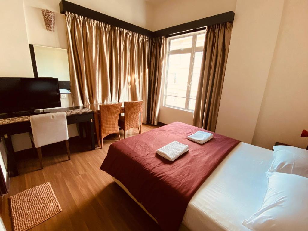 a hotel room with a bed and a desk and a window at Homestay 3 rooms suite Apartment 8-10pax at Amari Villa Bukit Katil, Ayer Keroh Melaka in Melaka