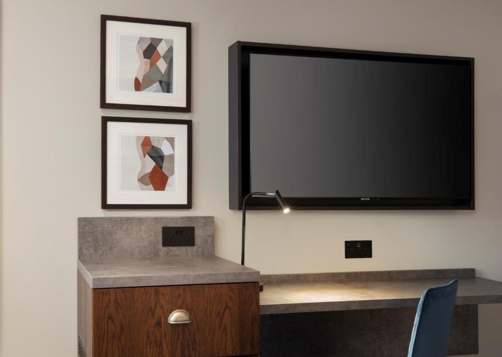 a flat screen tv hanging on a wall with a desk at Leonardo Royal Hotel Birmingham in Birmingham
