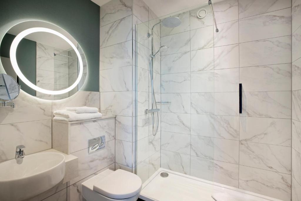 a bathroom with a shower and a toilet and a sink at Leonardo Royal Hotel Birmingham in Birmingham