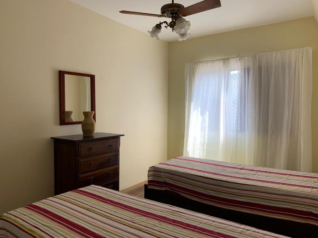 een slaapkamer met 2 bedden, een dressoir en een raam bij Condomínio Maitinga. (Pé na areia) in Bertioga