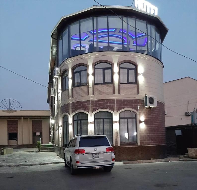a building with a car parked in front of it at EMIR PLAZA HOTEL in Türkistan