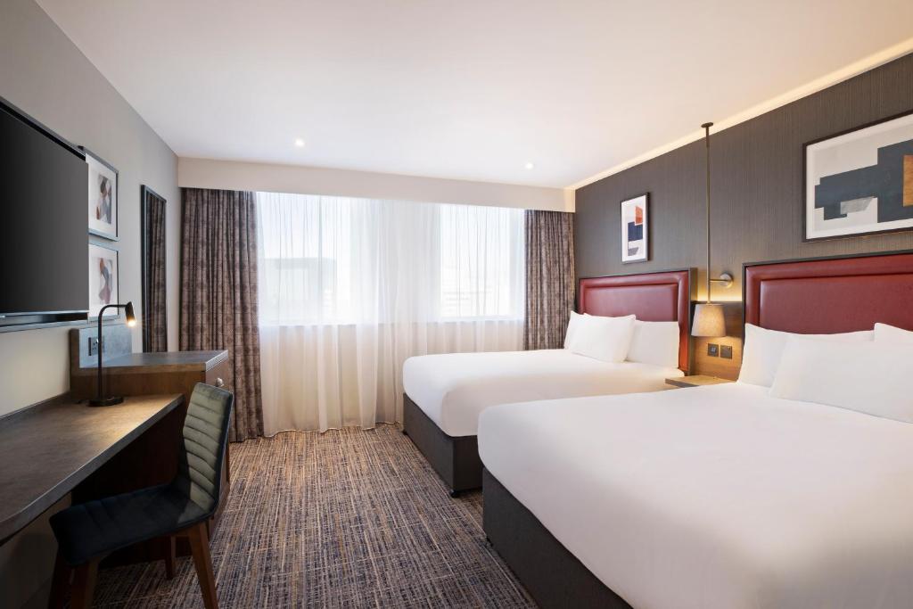 a hotel room with two beds and a desk at Leonardo Royal Hotel Birmingham in Birmingham