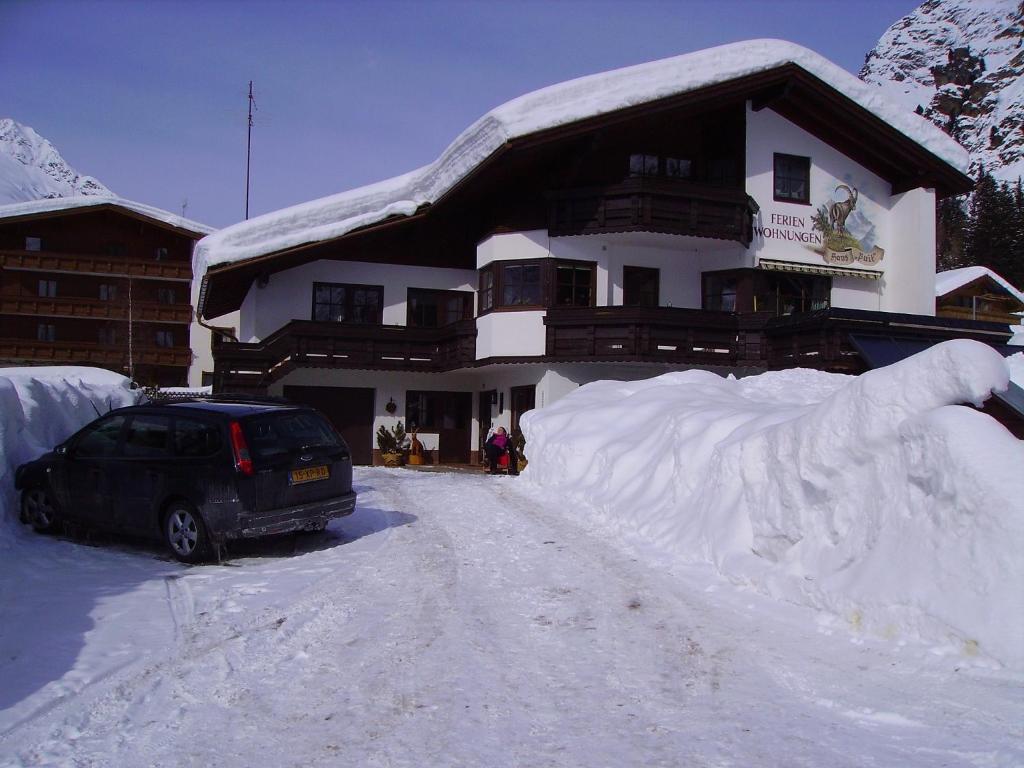 un coche aparcado frente a una casa cubierta de nieve en Haus Puit Mandarfen Pitztal, en Sankt Leonhard im Pitztal