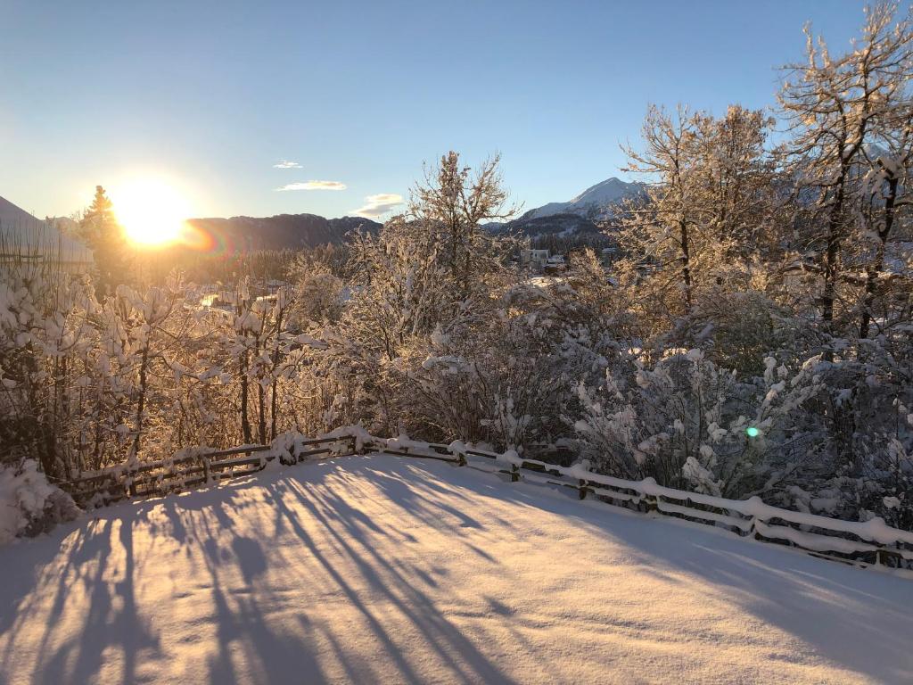 a road covered in snow with the sun in the background at Apartment Residenza Quadra Flims in Flims