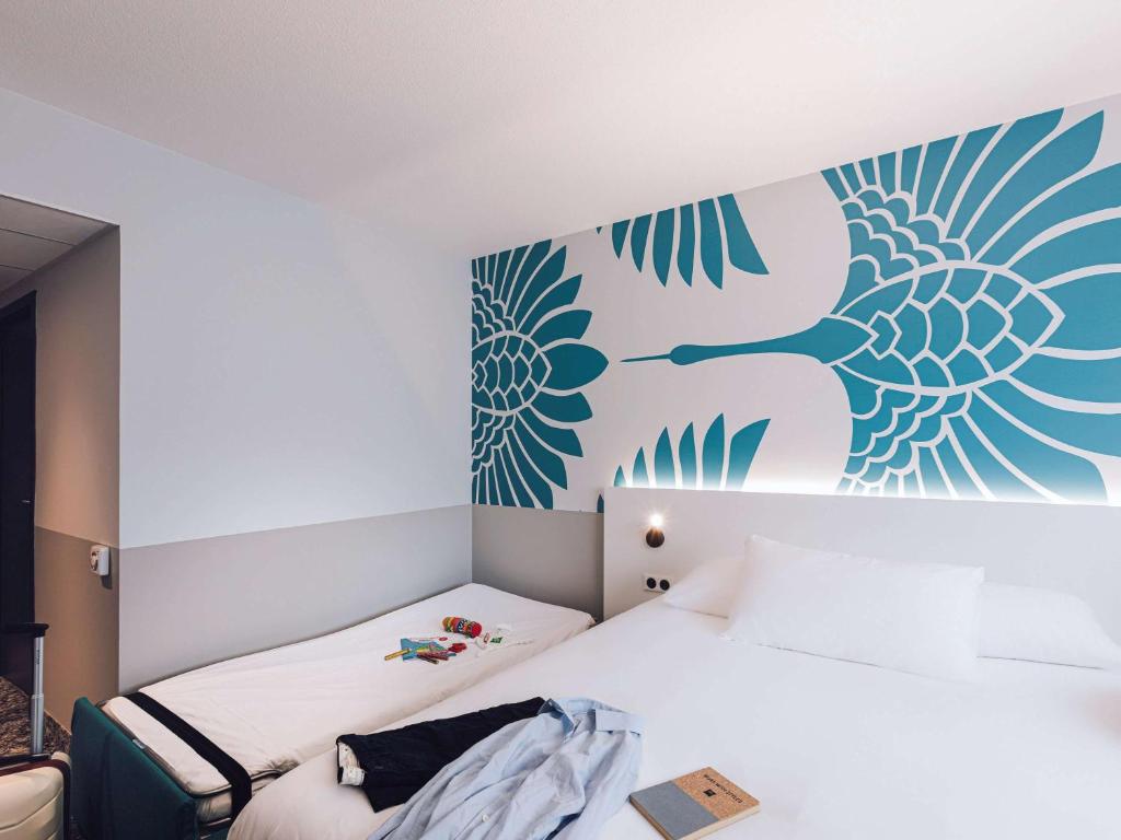 1 dormitorio con 1 cama y un mural en la pared en ibis Styles Nancy Laxou, en Nancy
