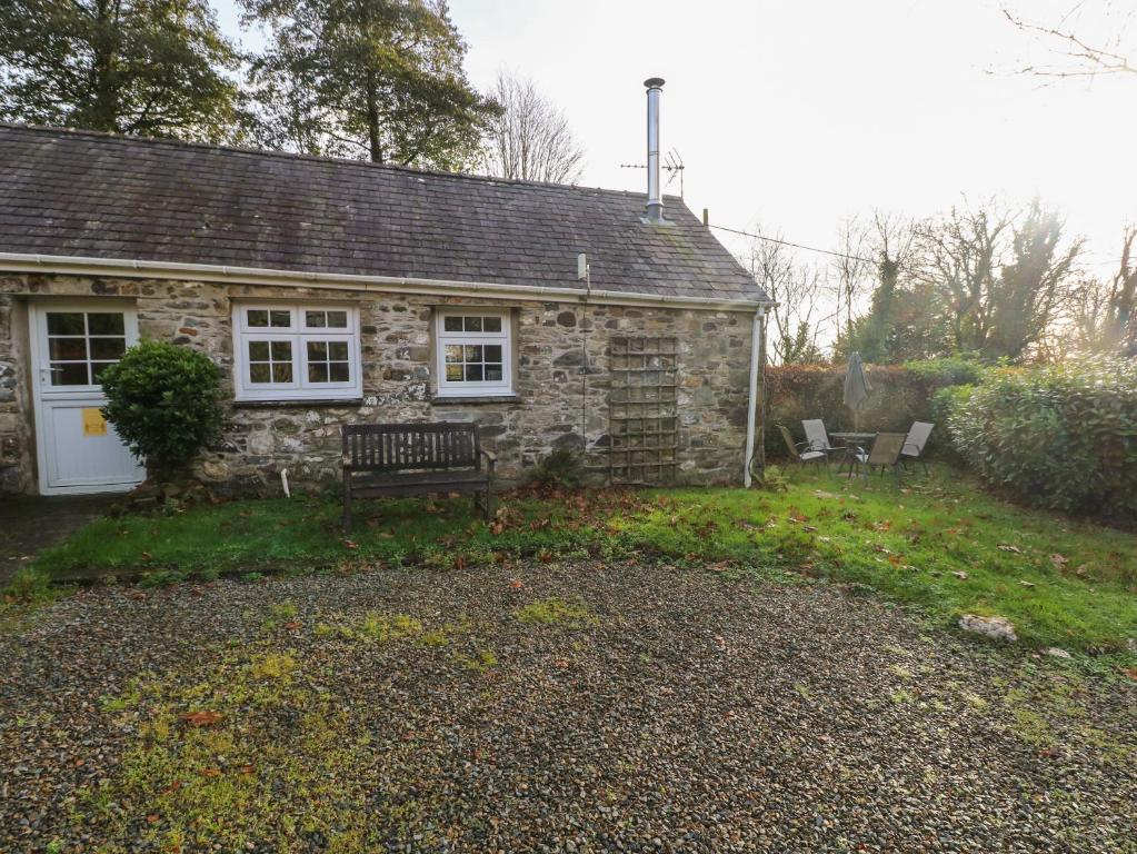 una casa de piedra con un banco delante en Knap Cottage en Walton East