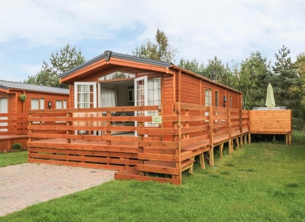 una cabaña de madera con una valla alrededor en Angie's Haven, Superb 2 Bedroom Lodge with Hot Tub - Sleeps 6 - Felmoor Park, en Morpeth