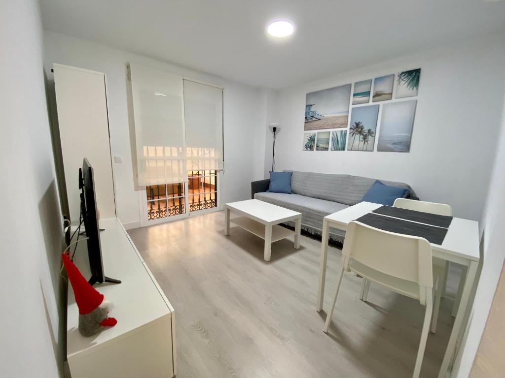 een woonkamer met een bank, een tafel en een tv bij Las Arenas de la Carihuela in Torremolinos