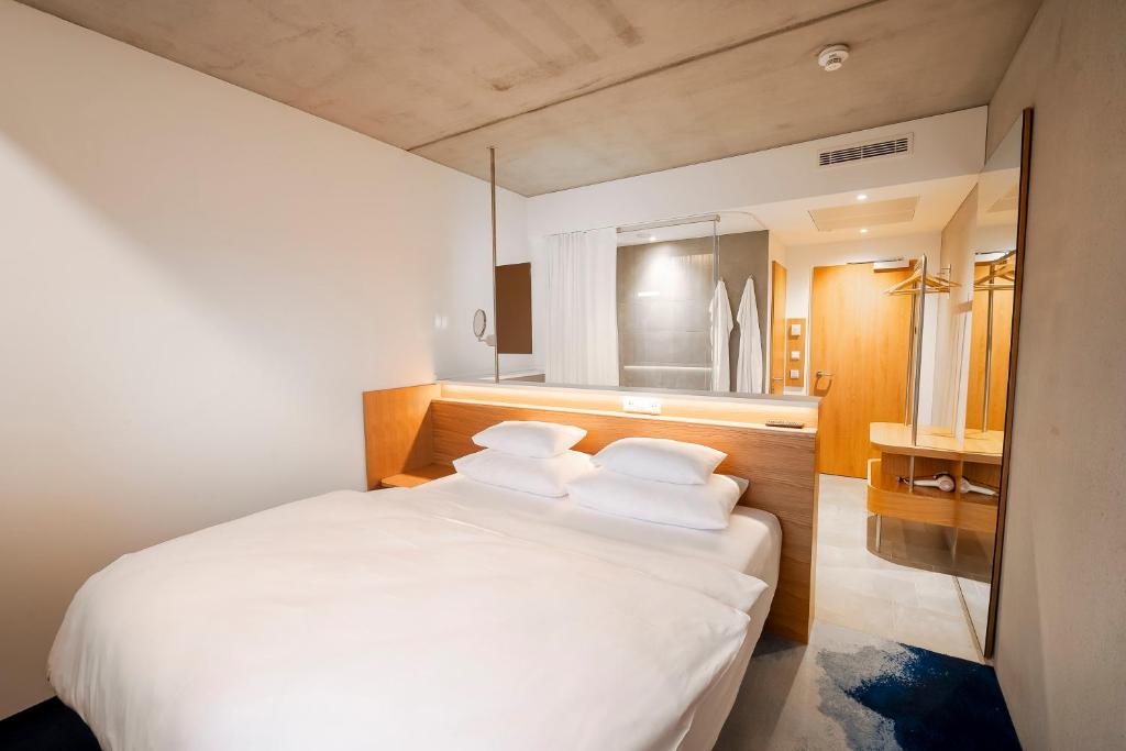 una camera con letto bianco e 4 cuscini di FIRMAMENT Hotel a Feldkirch