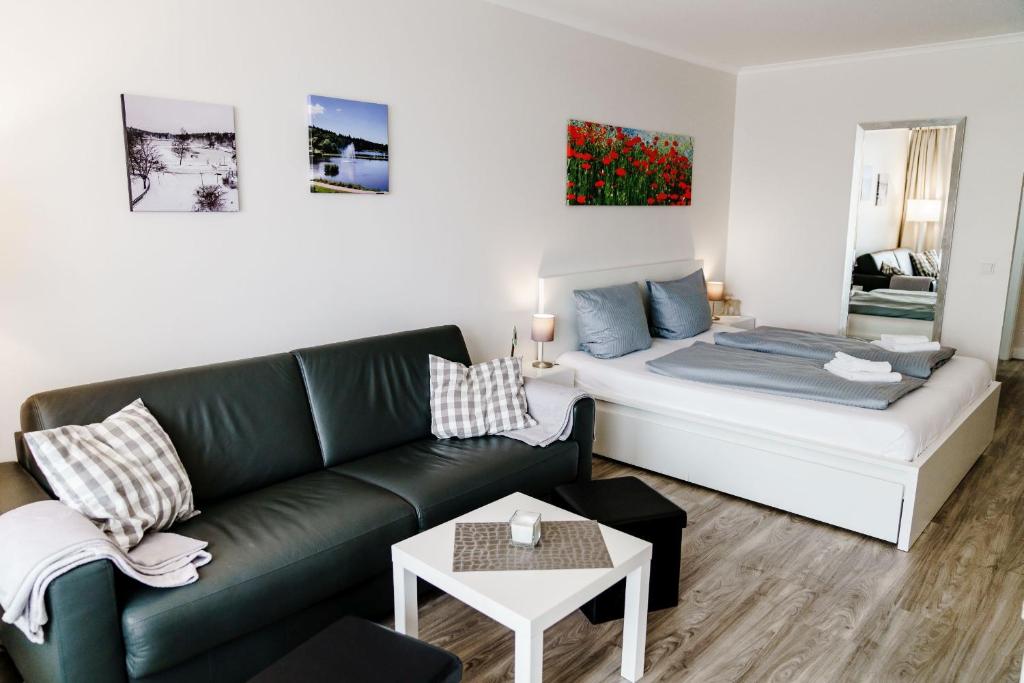 - un salon avec un canapé et un lit dans l'établissement Haus Vier Jahreszeiten am See Apartment am Kranichsee, à Hahnenklee