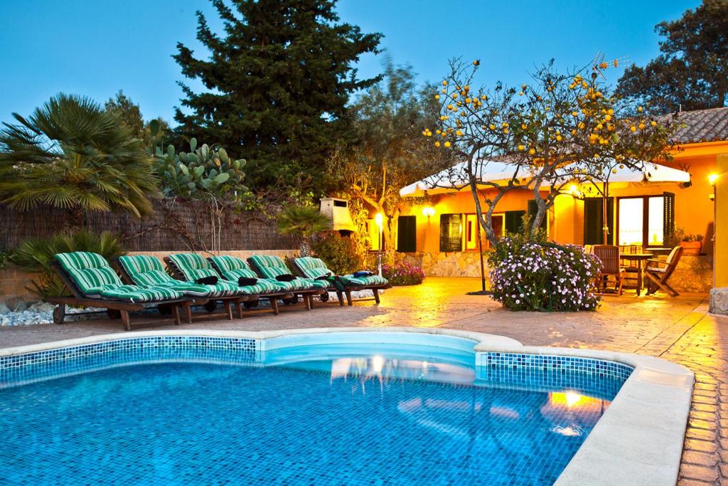 a swimming pool in a yard with chairs and a house at Villa El Mal Pas / Can Seguinet in Alcudia
