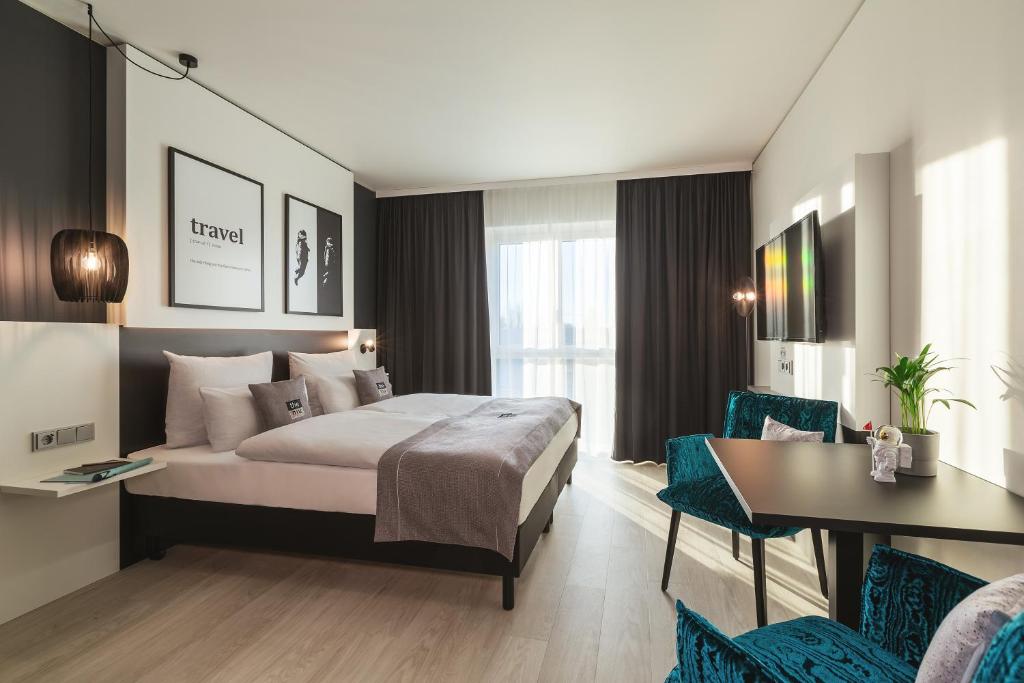 Habitación de hotel con cama, mesa y sillas en the niu Star - Apartments, en Sindelfingen