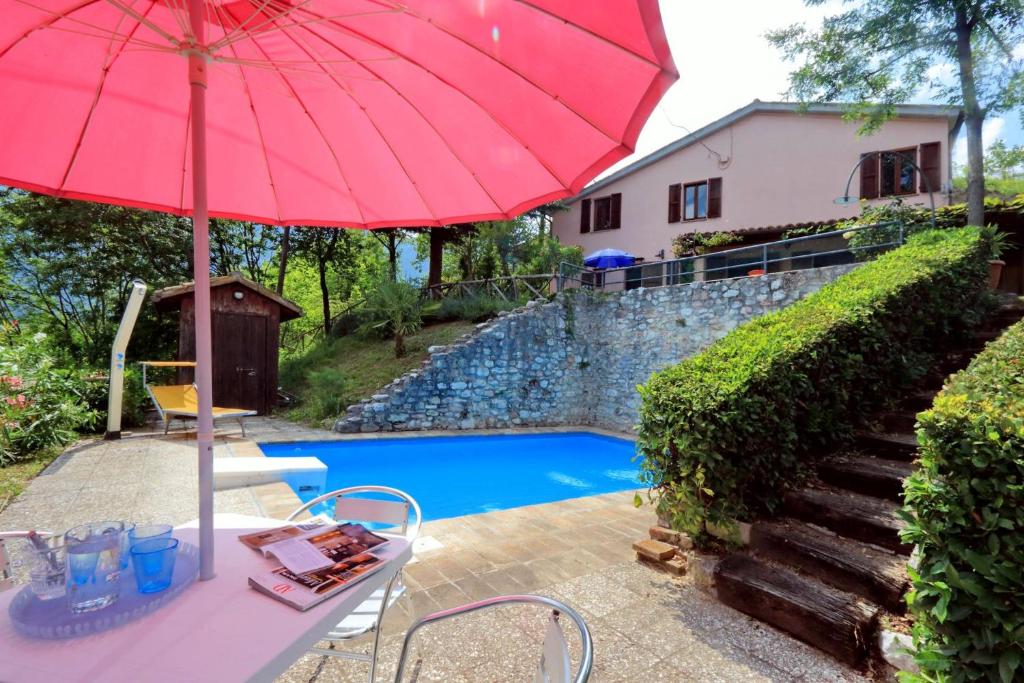 a table with an umbrella next to a swimming pool at Villa Acacie in Sarnano