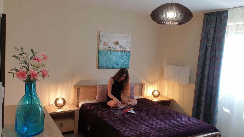 kobieta siedząca na łóżku w sypialni w obiekcie BástyaVár Családi Apartmanház - Gyula w mieście Gyula
