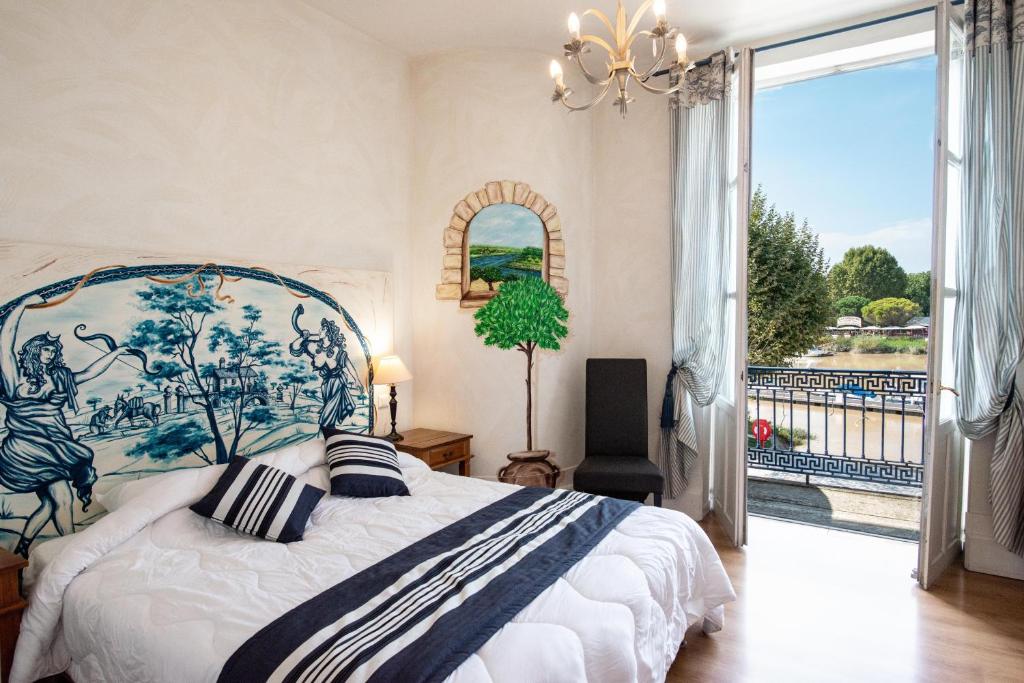 een slaapkamer met een groot bed en een groot raam bij Logis Hôtel de la Tour in Libourne