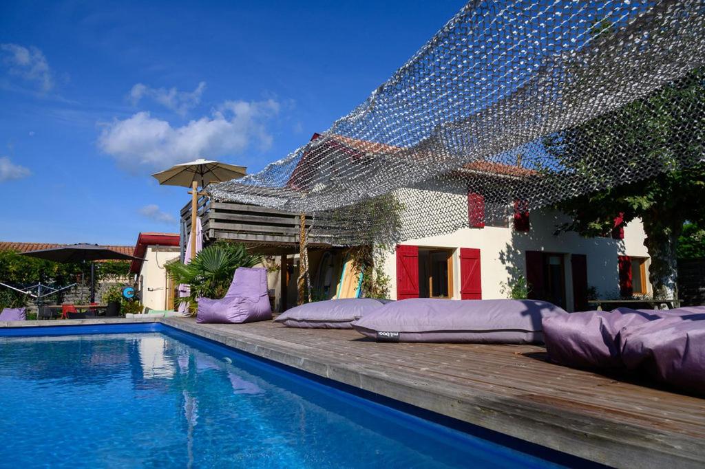 una piscina con almohadas moradas junto a una casa en The Secret Spot Lodge, en Azur