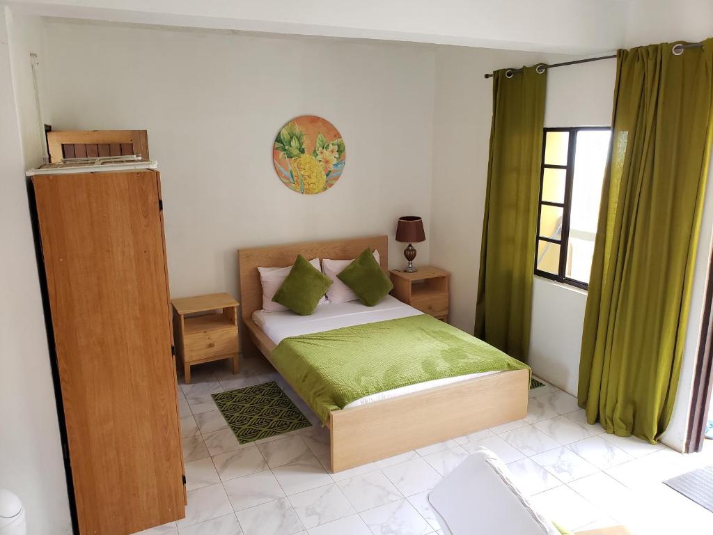 Schlafzimmer mit einem Bett mit grüner Bettwäsche und einem Fenster in der Unterkunft Bay View Studio Apartment 3B - Canouan Island in Canouan
